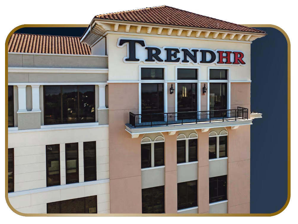Exterior view of a beige and light brown multi-story office building with a red tile roof and large windows, featuring the sign 'TREND HR' in bold letters on the upper corner.