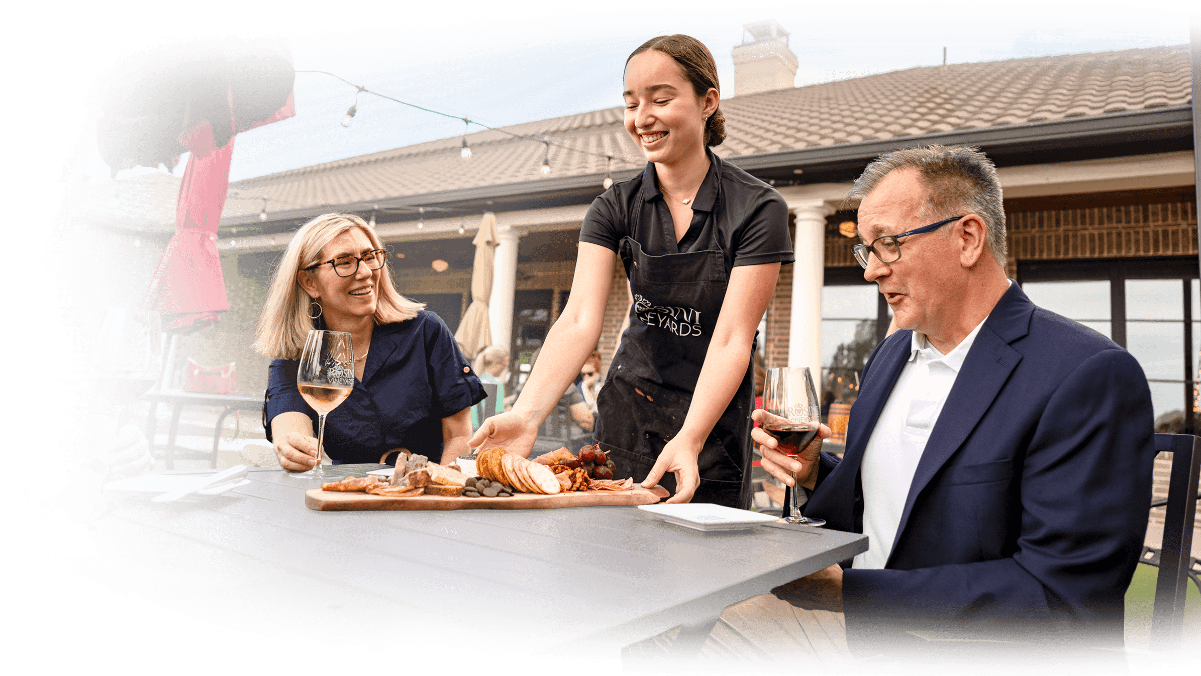 Friends sharing wine and a charcuterie board on a winery patio