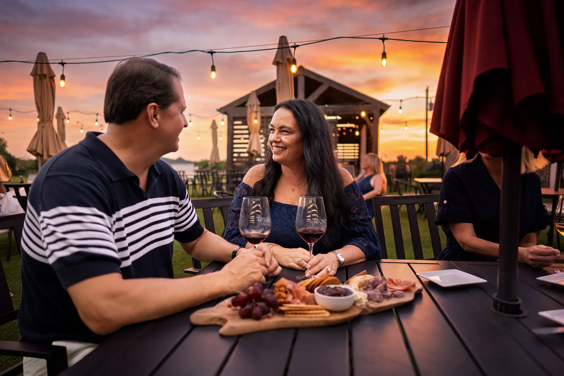 Couple sharing wine and a charcuterie board on a patio at sunset in Rockwall
