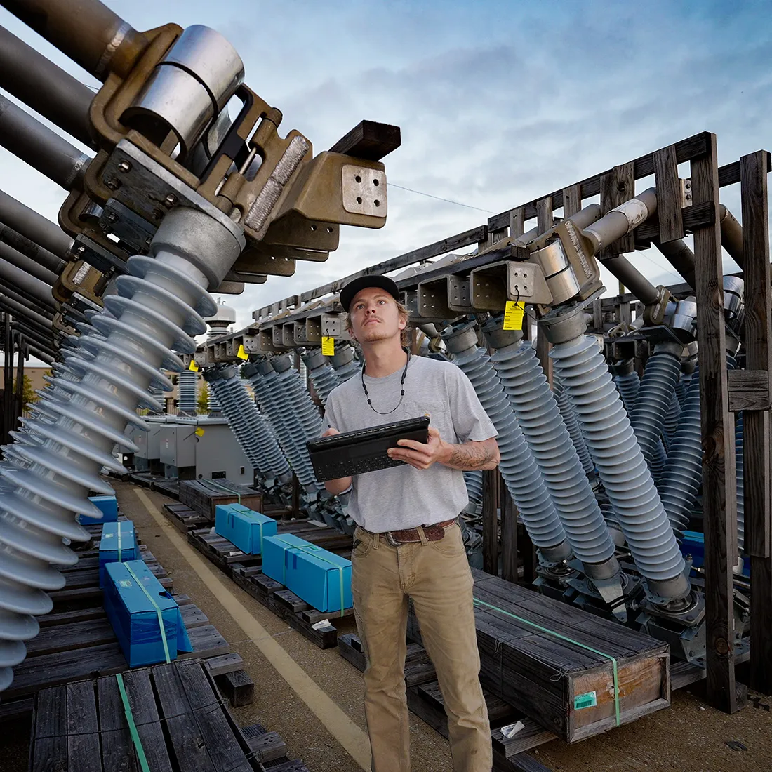 Engineer with a tablet inspecting high-voltage switchgear at a substation