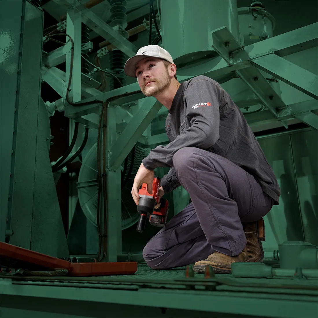 Technician using a power drill on industrial equipment