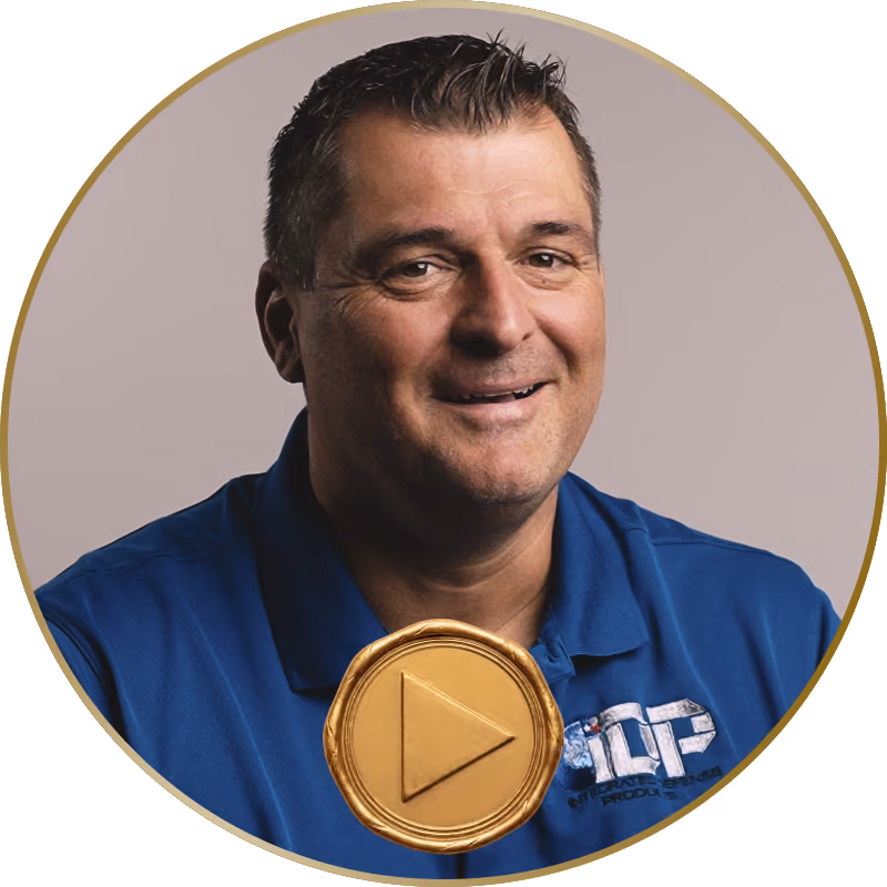 Man with short dark hair smiling, wearing a blue polo shirt with a logo on the left side.