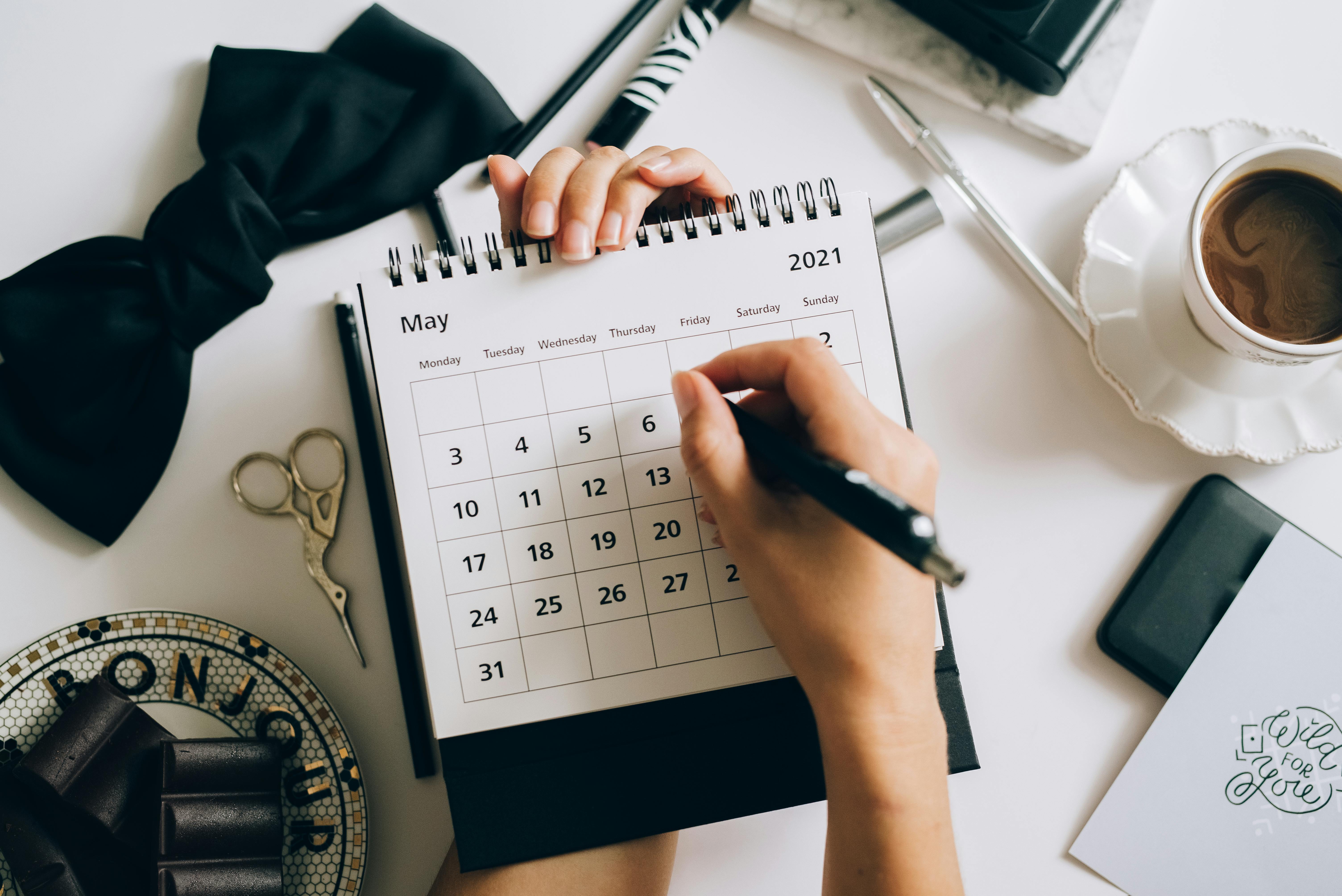 Person writing on a desk calendar to schedule