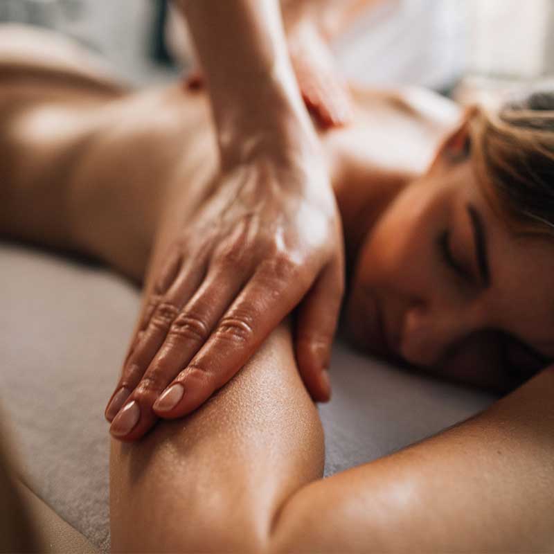 A woman receives a relaxing shoulder and arm massage lying face down on a massage table.