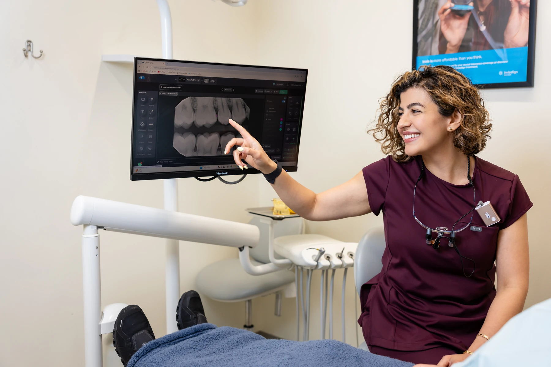 Dentist pointing out findings on a digital X-ray for a patient in the treatment room