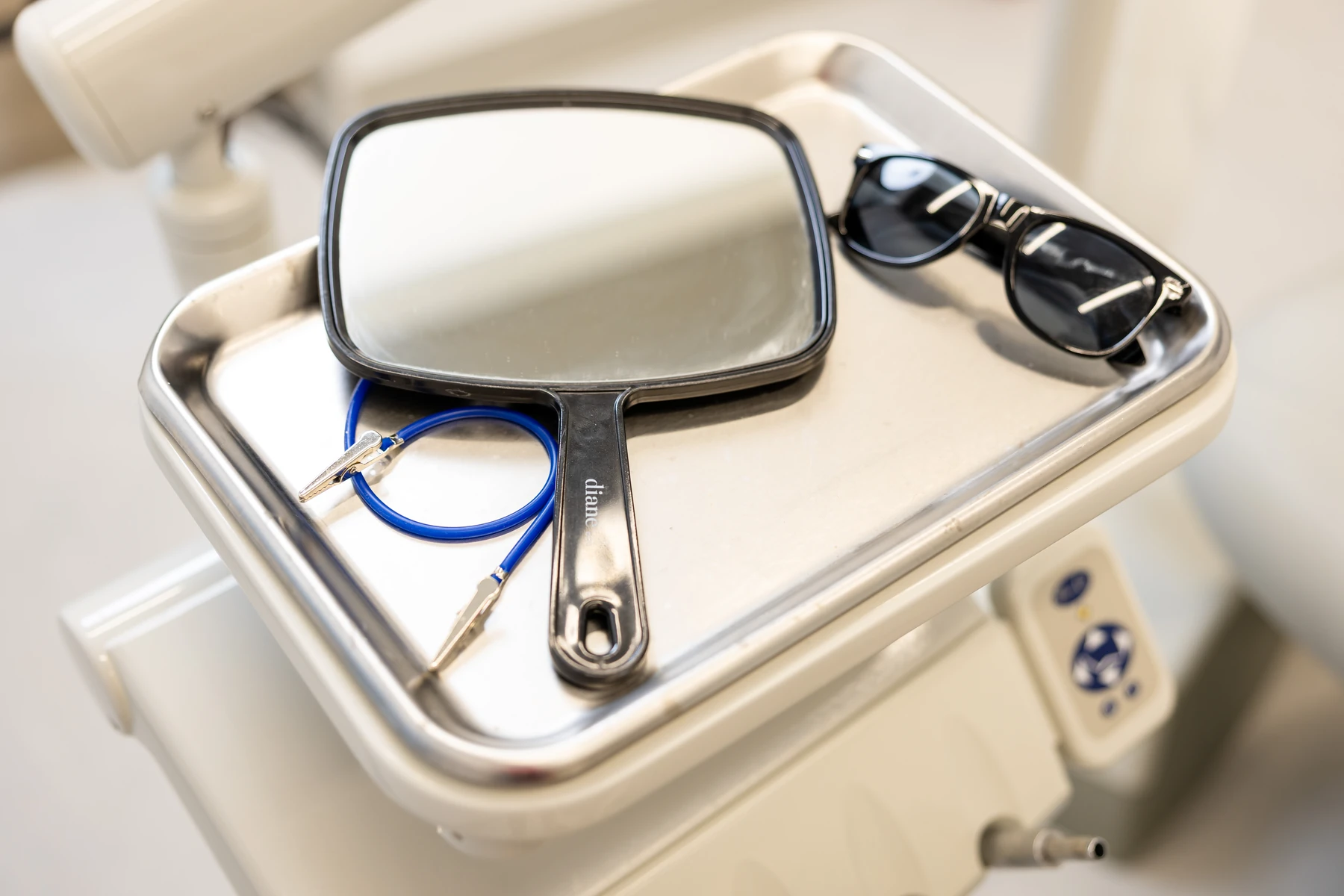 Hand mirror and patient sunglasses on a tray beside the dental chair at Dentist Downtown Seattle