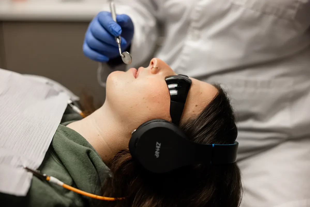 Dentist treating a patient who is resting comfortably with headphones