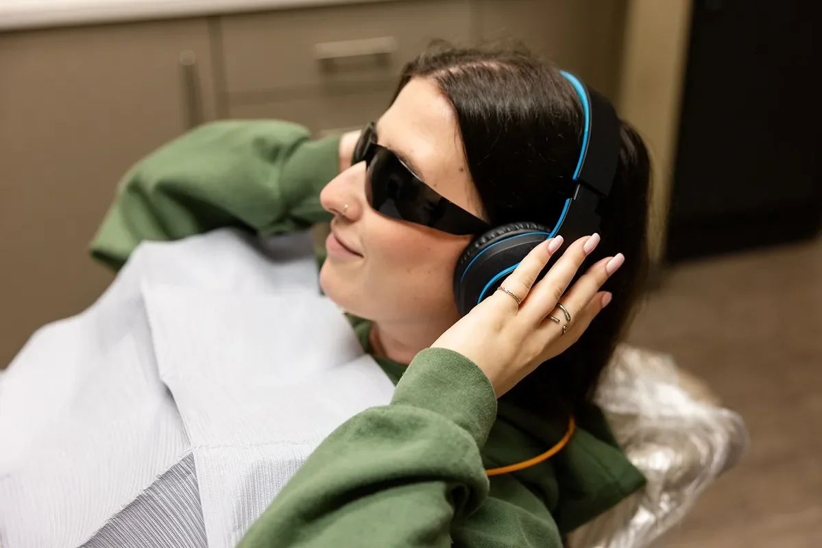Patient relaxing in the dental chair with headphones and sunglasses
