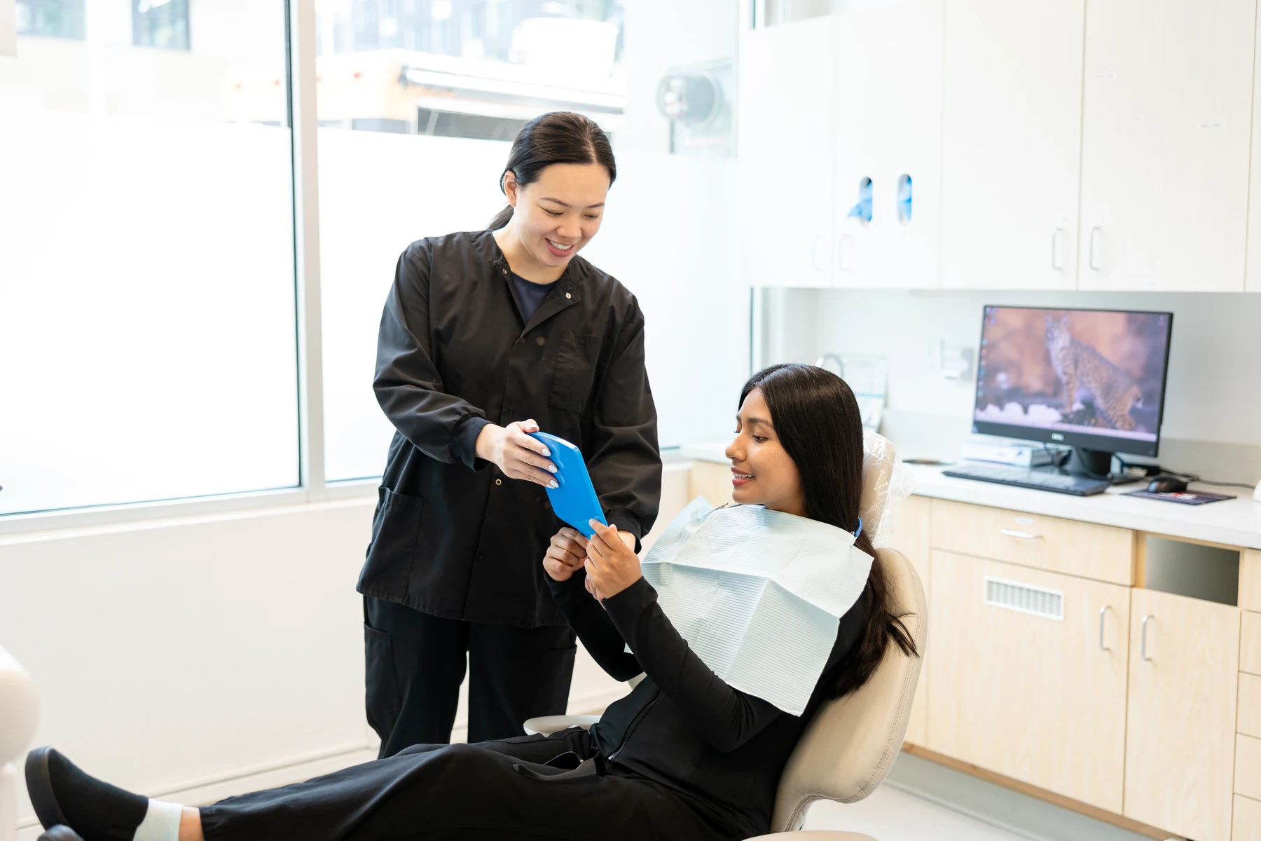Patient viewing her smile in a handheld mirror during a visit