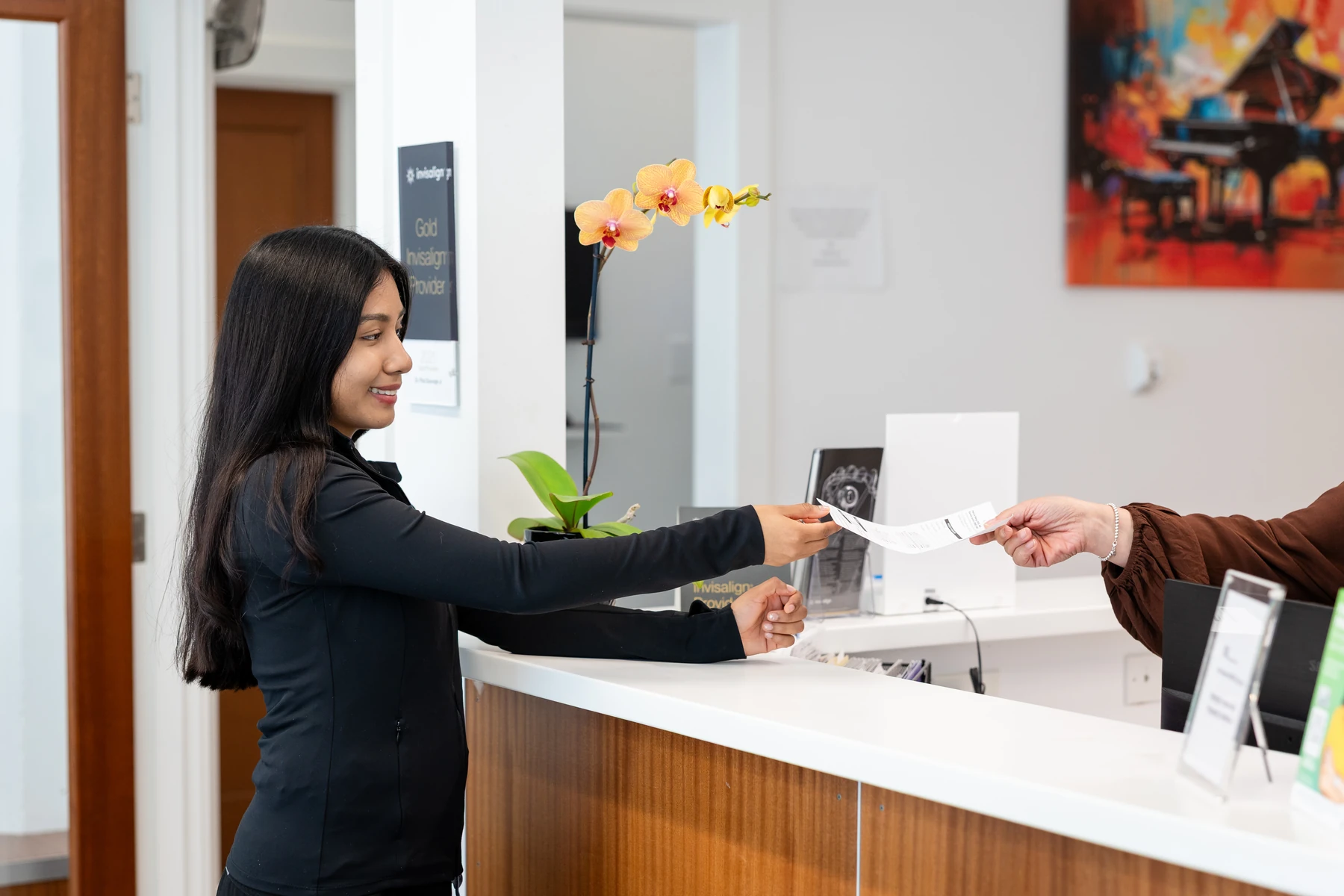 Patient at the front desk beneath the practice's Gold Invisalign Provider sign