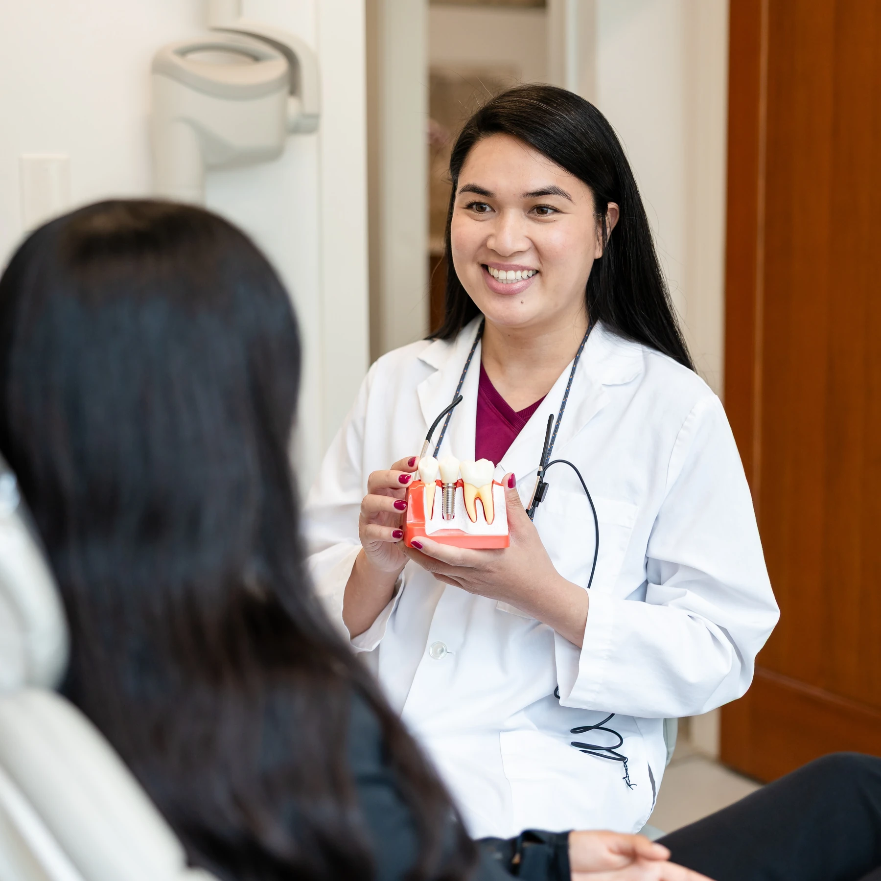 Dr. Sabrina showing a patient a model of a tooth and its roots