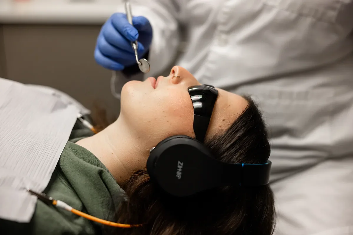 Dentist performing a procedure on a patient resting with headphones
