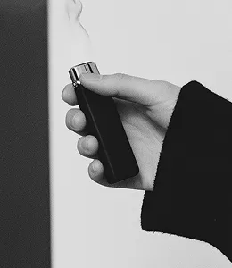 Black and white photo of a hand holding a lit lighter with smoke.