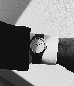 Close-up black and white photo of a classic wristwatch on a wrist.
