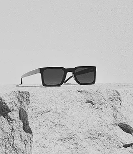 Minimalist black and white photo of sunglasses placed on a rough rock.