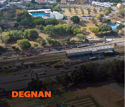 Aerial view of train yard with multiple tracks, trains, and green trees around a residential area.