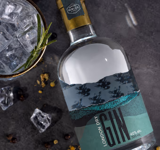 Bottle of London Dry Gin with 40% alcohol and a glass with ice and a rosemary sprig on a dark surface. (Abode Firefly)