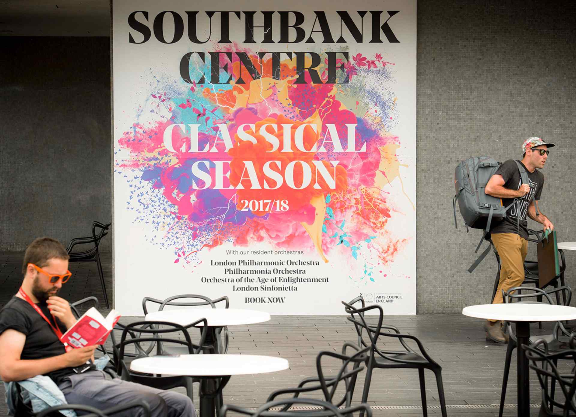 A visitor reading beside a Southbank Centre concert poster, a short walk from Stow Away Waterloo