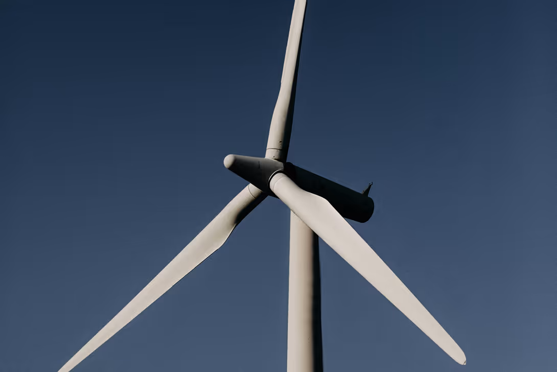 Close-up of white wind turbine blades against a clear deep blue sky.