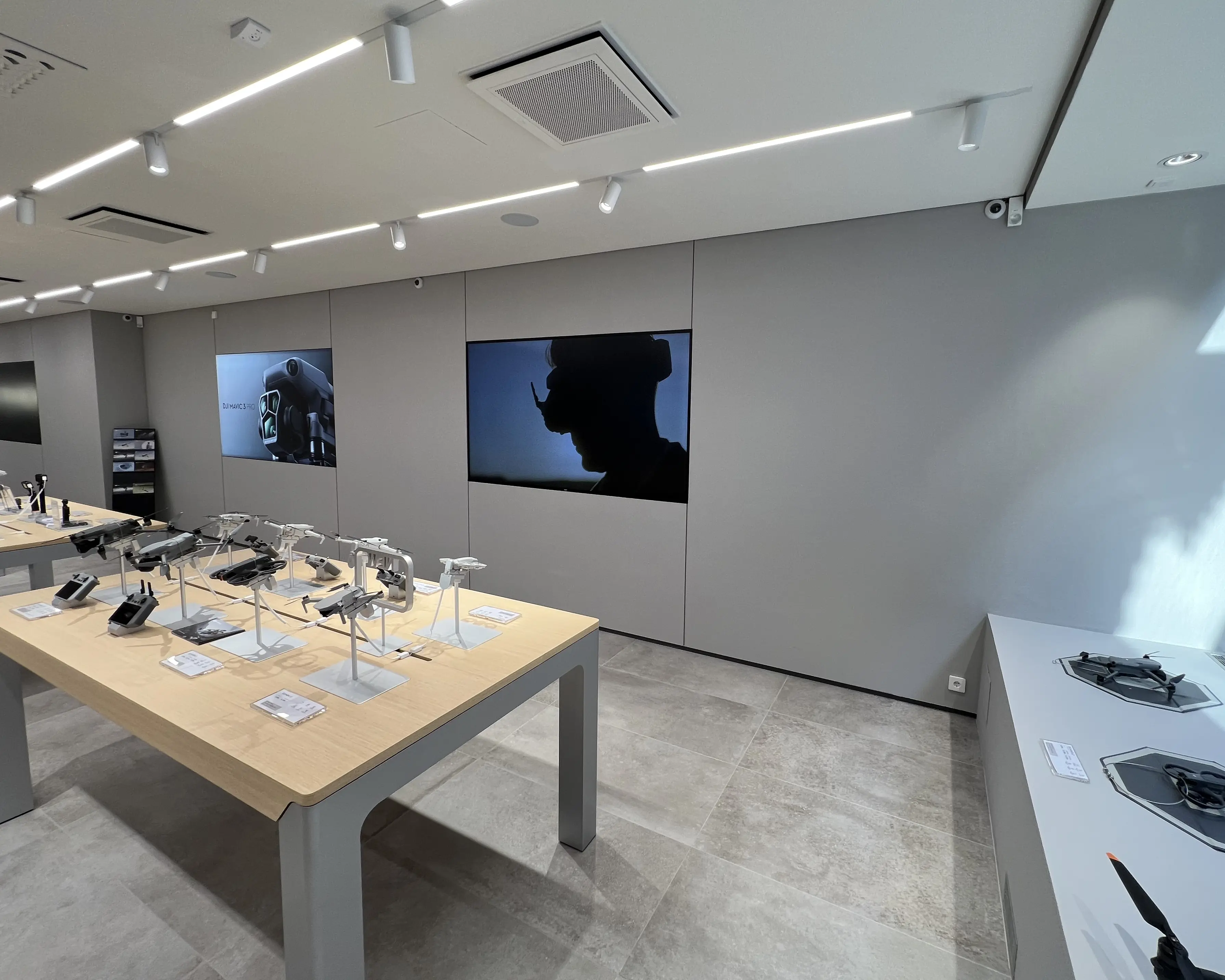 Modern store interior with tables displaying drones and screens showing drone-related images on the wall.