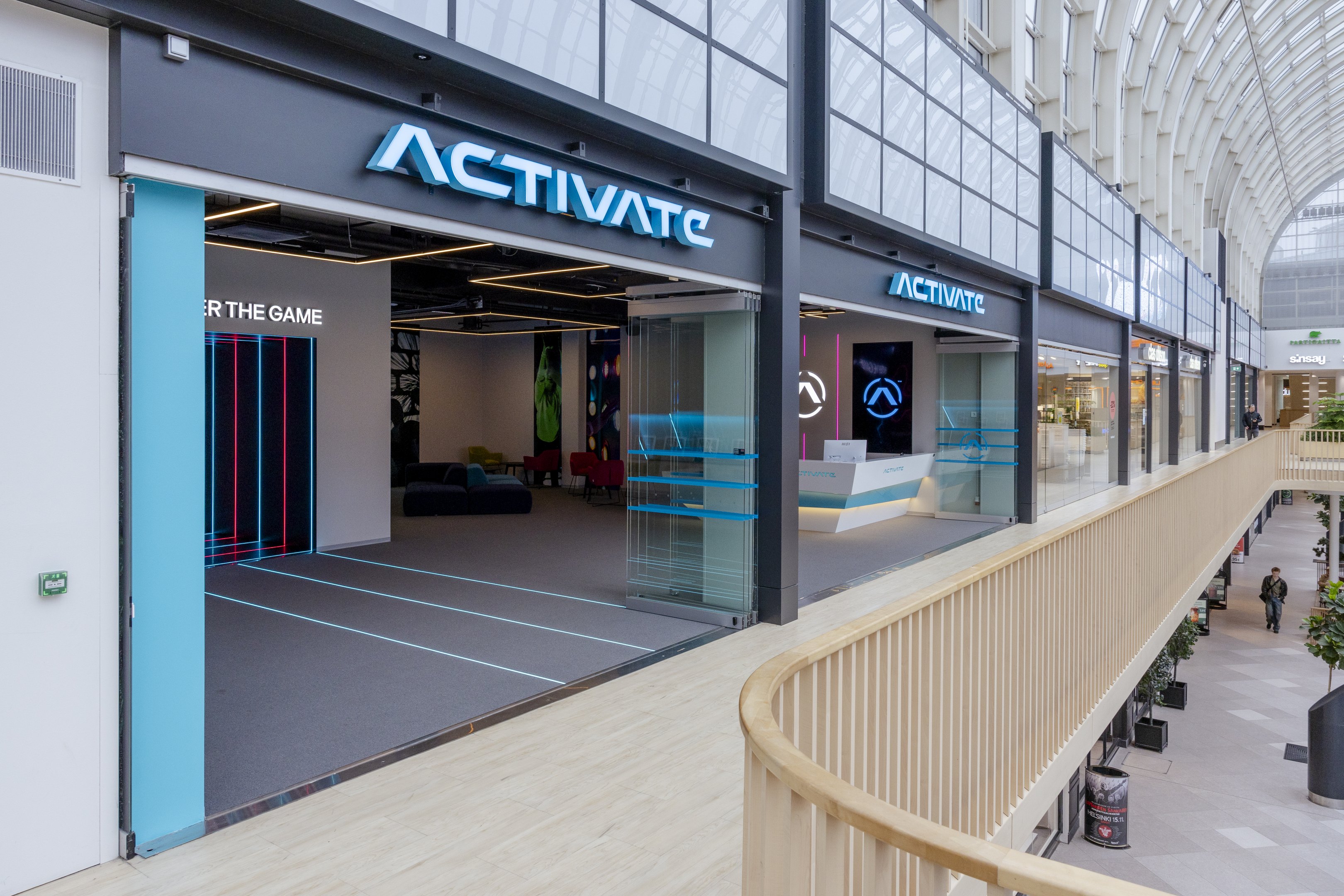 Modern Activate store interior with neon blue lighting and glass walls in a shopping mall upper level.