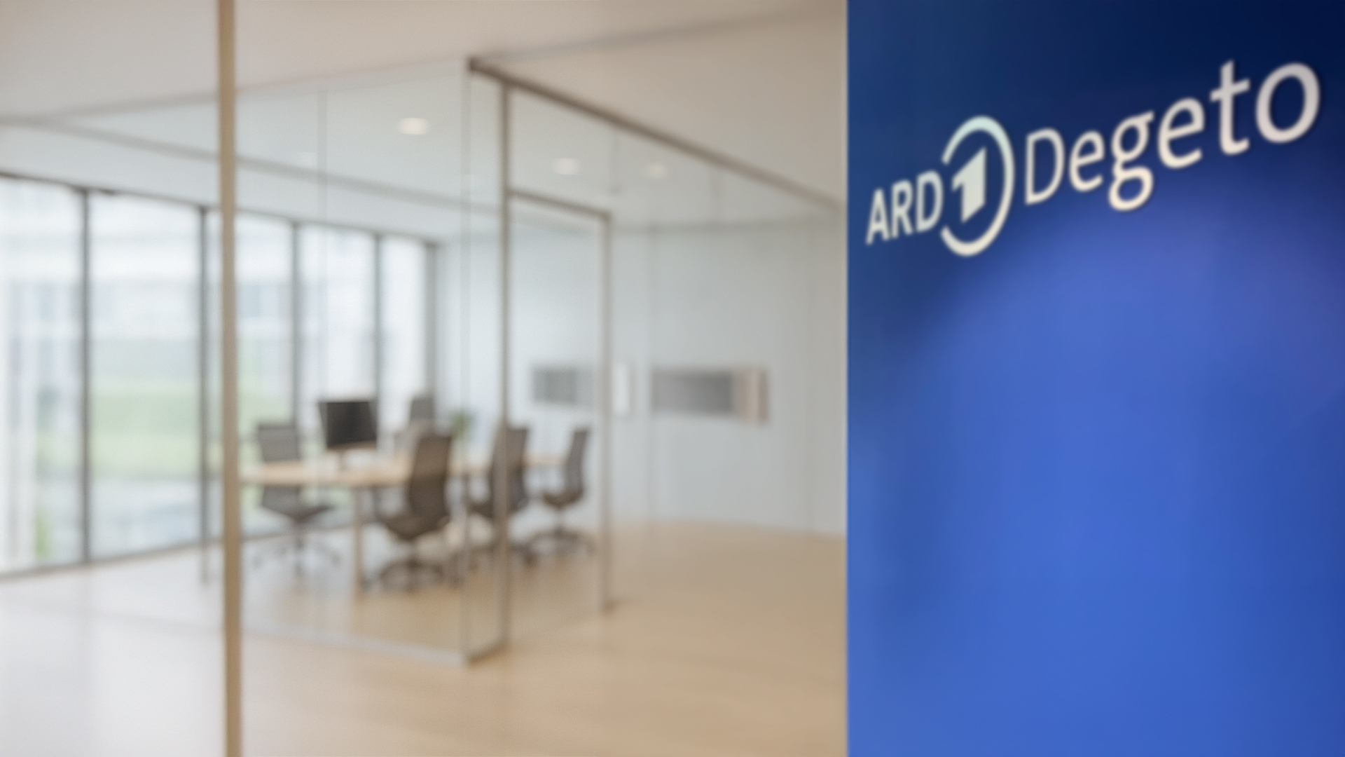 Büroräume der ARD Degeto: Besprechungsraum hinter Glas, daneben das ARD-Degeto-Logo auf blauer Wand