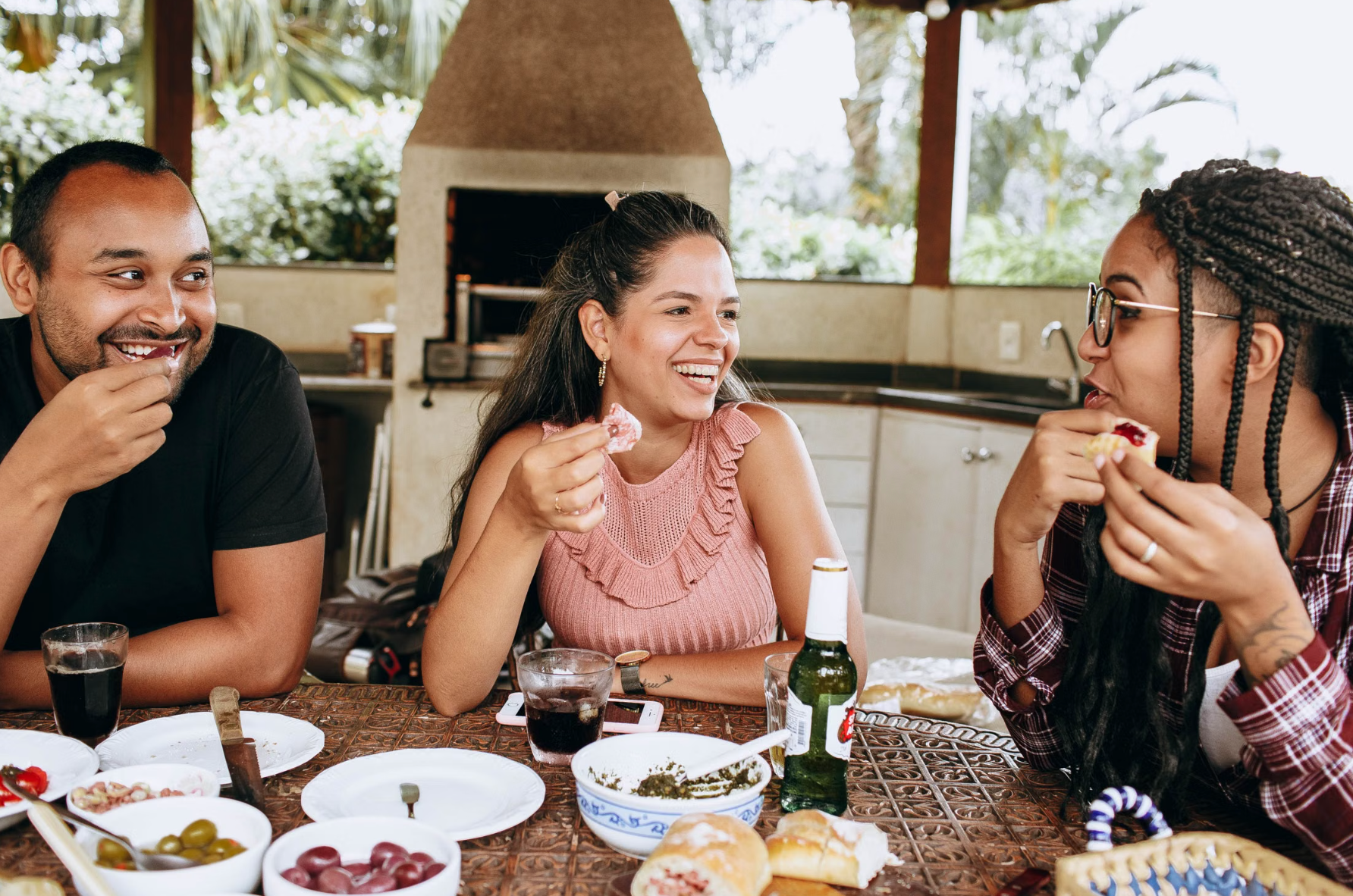 Three friends sharing a meal outdoors, the kind of relaxed gathering Dominicans make sancocho for every Sunday and special occasion.