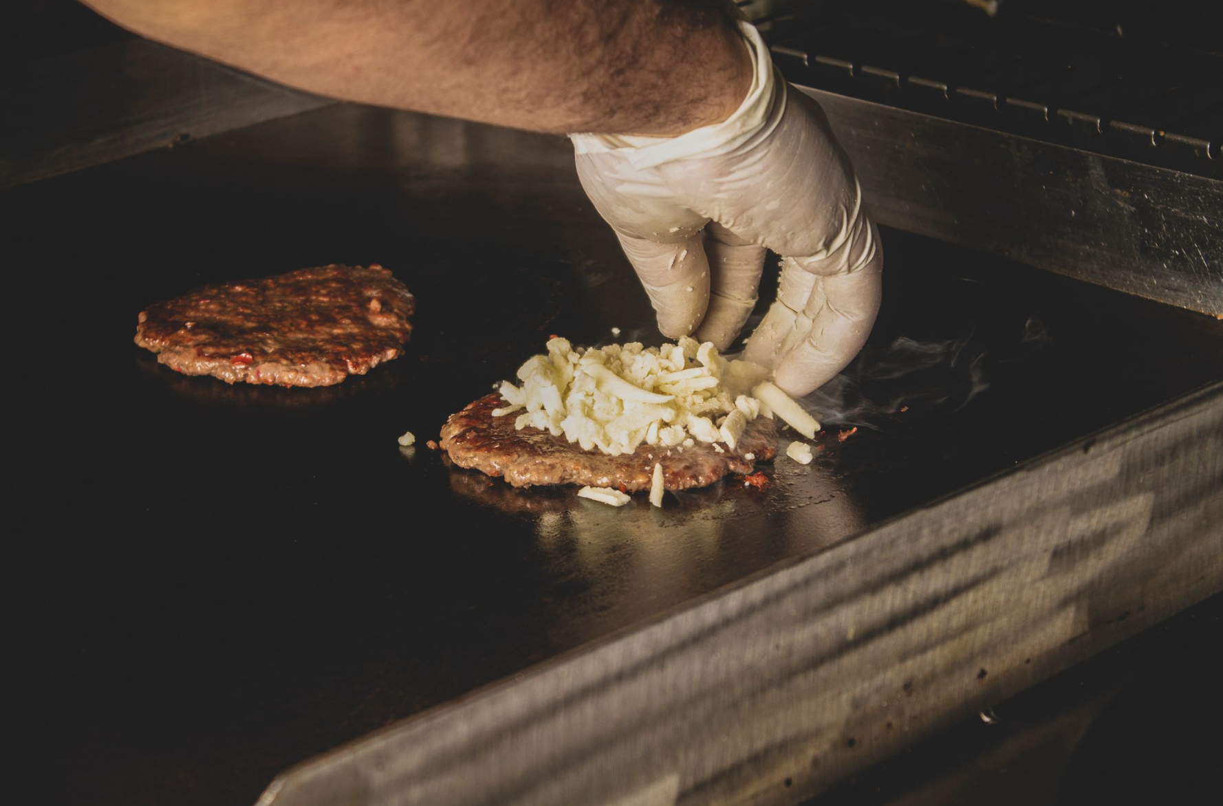 A beef patty cooking on a hot griddle the base of the Dominican chimichurri burger, or chimi, the country's most iconic late-night street food