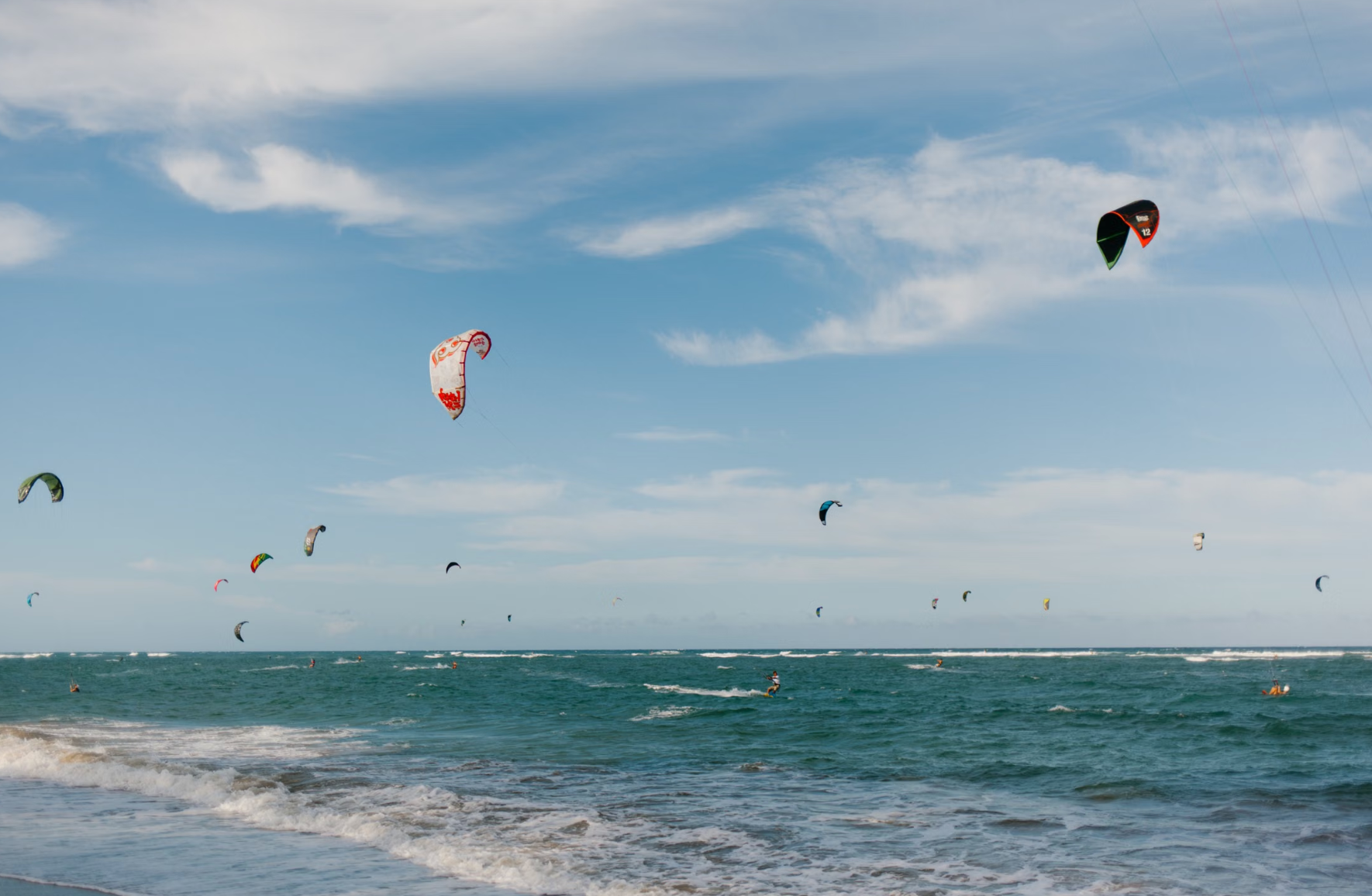 Kitesurfer flying above shallow turquoise lagoon water. 