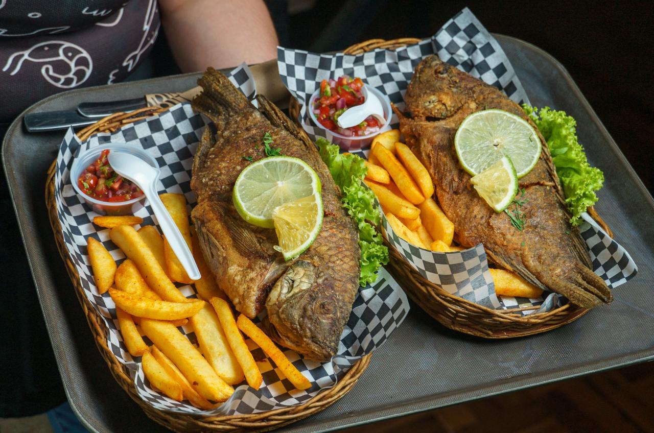 Two whole fried fish served in baskets with chips lime wedges salsa and lettuce at a Dominican Republic seafood restaurant.