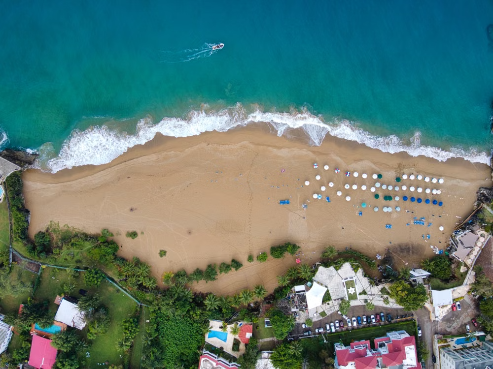 Golden sandy Playa Dorada beach with calm Atlantic water and palm trees Puerto Plata Dominican Republic