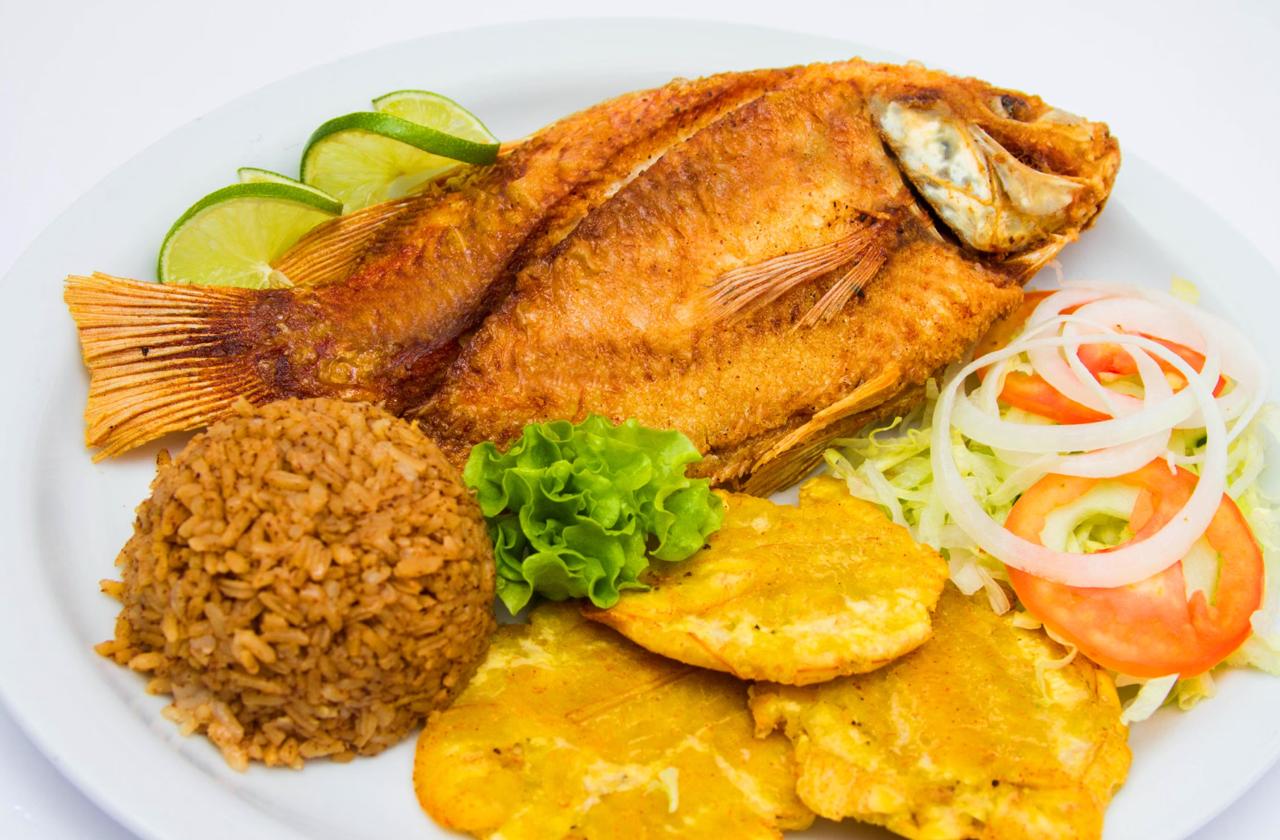 Dominican pescado frito, a whole fried fish served with seasoned rice, tostones and a fresh salad of shredded lettuce, onion and tomato