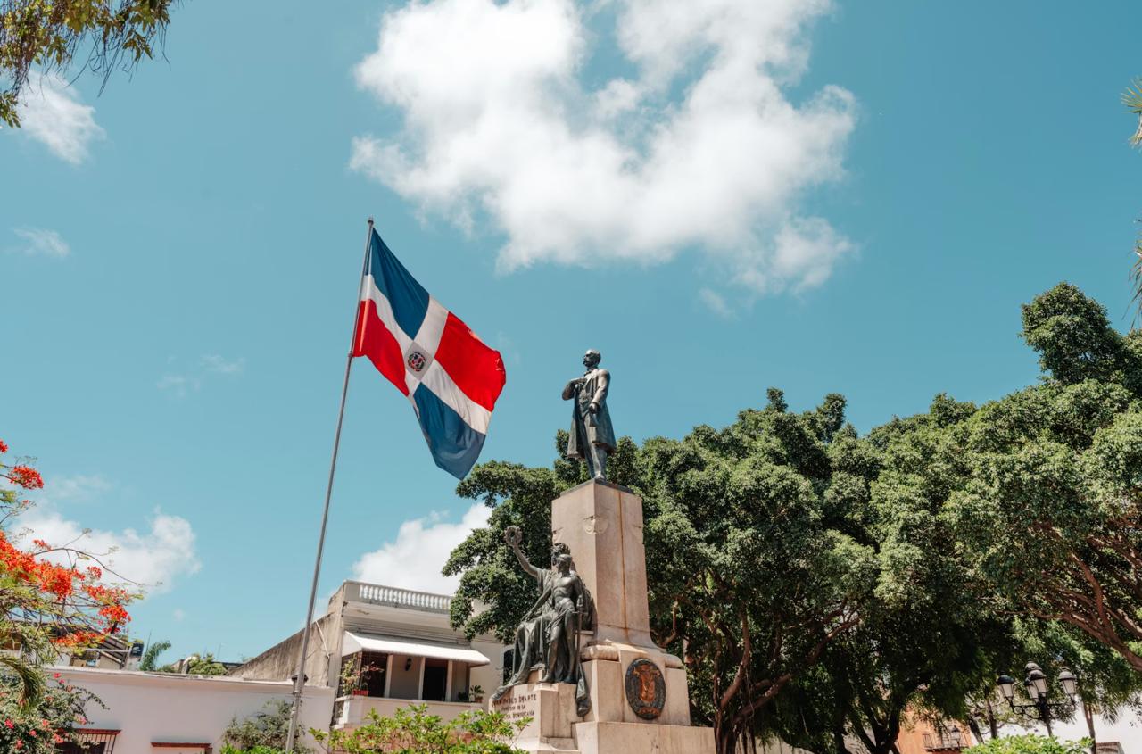 The national flag of the Dominican Republic showing the central white cross, coat of arms and an open Bible