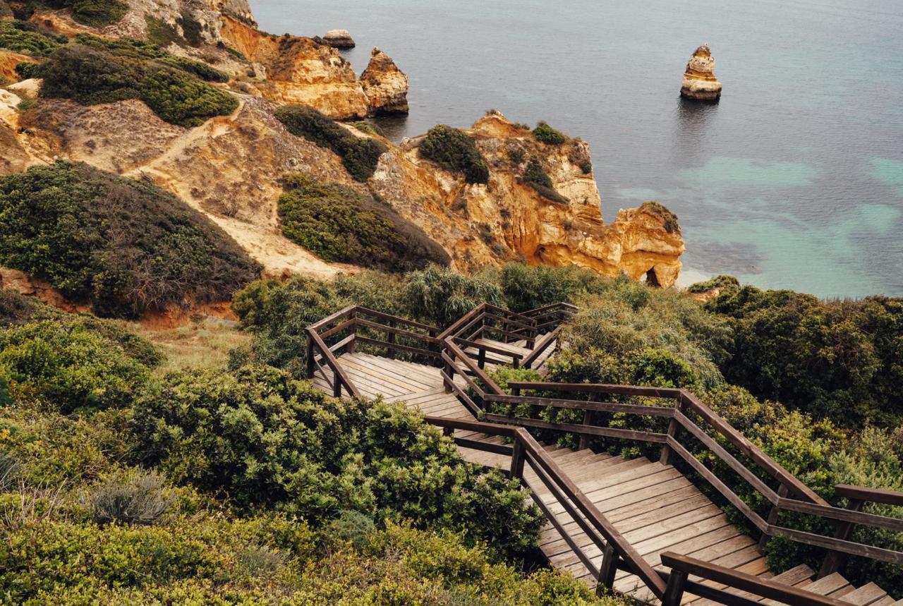 Wooden staircase descending the cliff to a sheltered cove beach, Lagos, Portugal