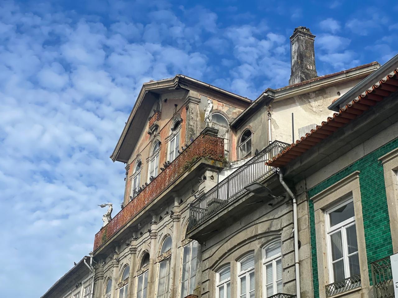 An ornate historic building facade with iron balconies, stone carvings, and green azulejo tiles in Lagos Portugal old town.