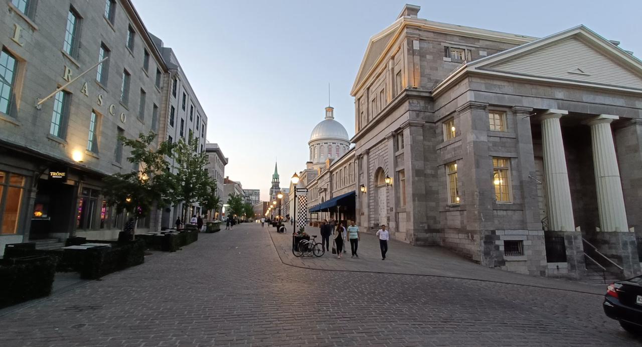 Cobblestone lane in Old Montreal lined with historic grey-stone buildings and a horse-drawn calèche