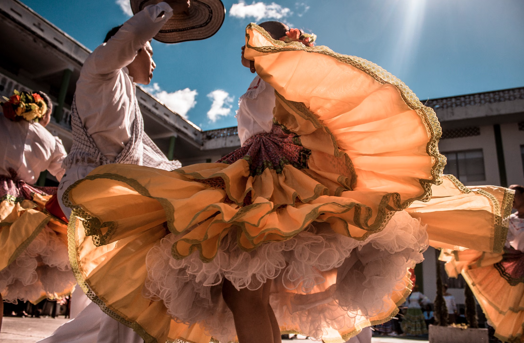 Dominican couple dancing merengue in traditional attire performing outdoors under the bright sun