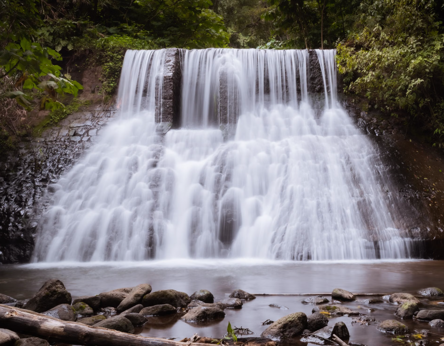 Rainforest waterfall pouring into natural swimming pool