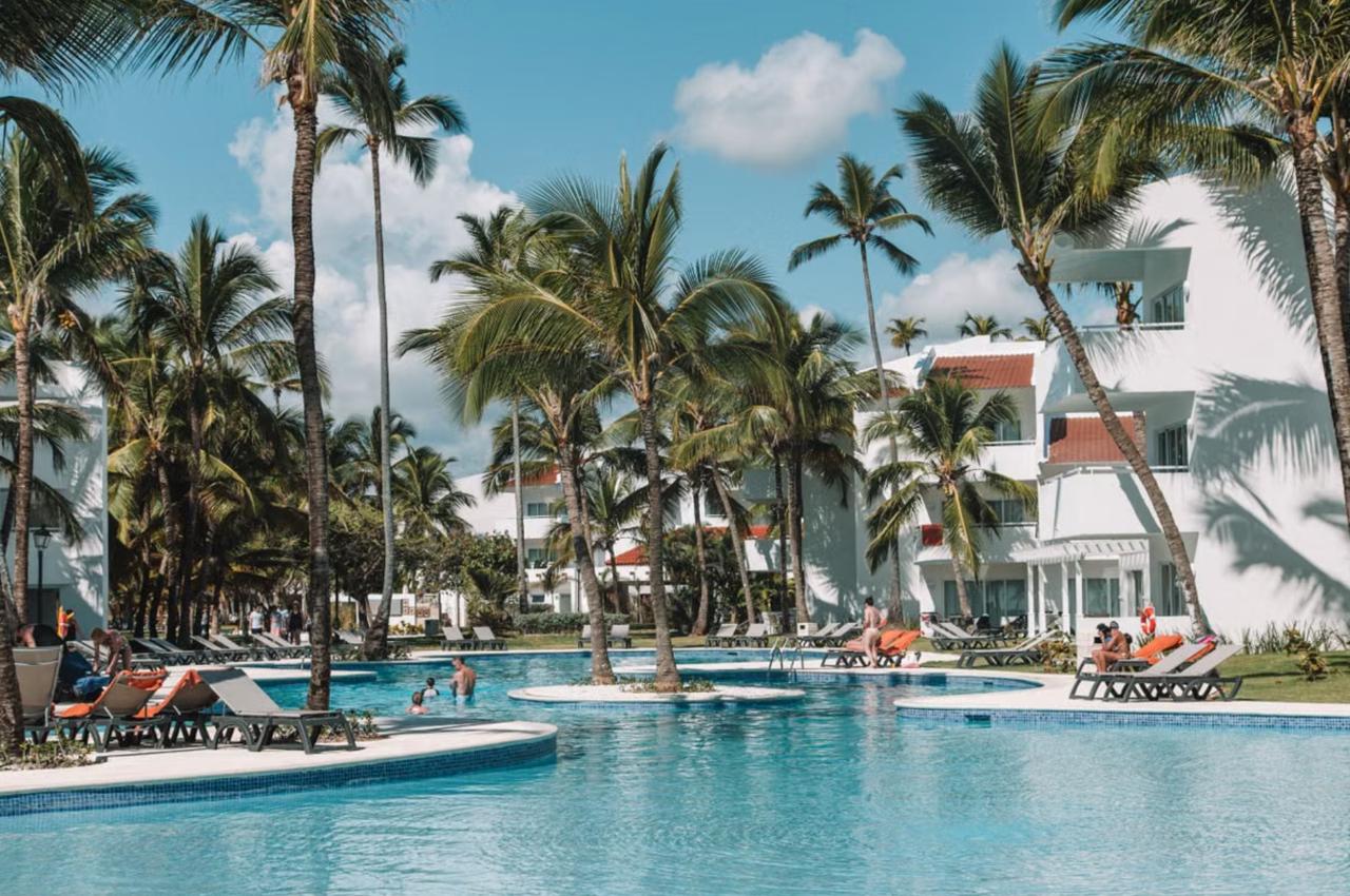 Beachfront all-inclusive resort pool in Bávaro, Punta Cana, with loungers, palm trees, and the sea in the background
