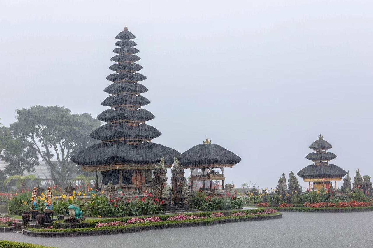 Scenic view of Ulun Danu Beratan Temple surrounded by lush greenery and vibrant flowers in the rain