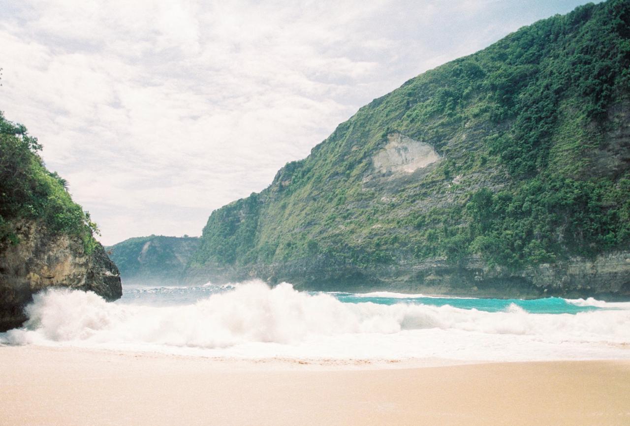 White sand beach surrounded by towering limestone cliffs Nusa