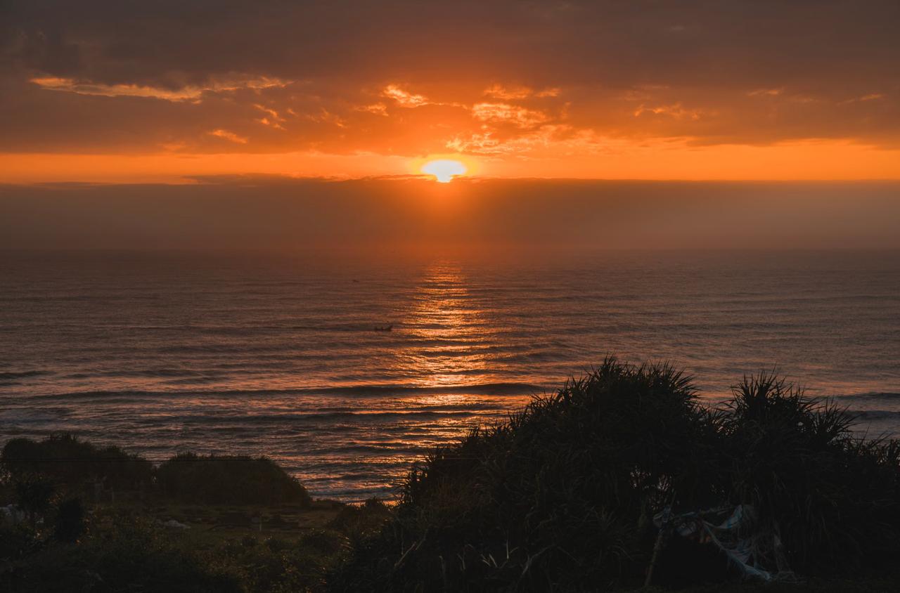 Golden sunset over ocean horizon viewed from clifftop restaurant