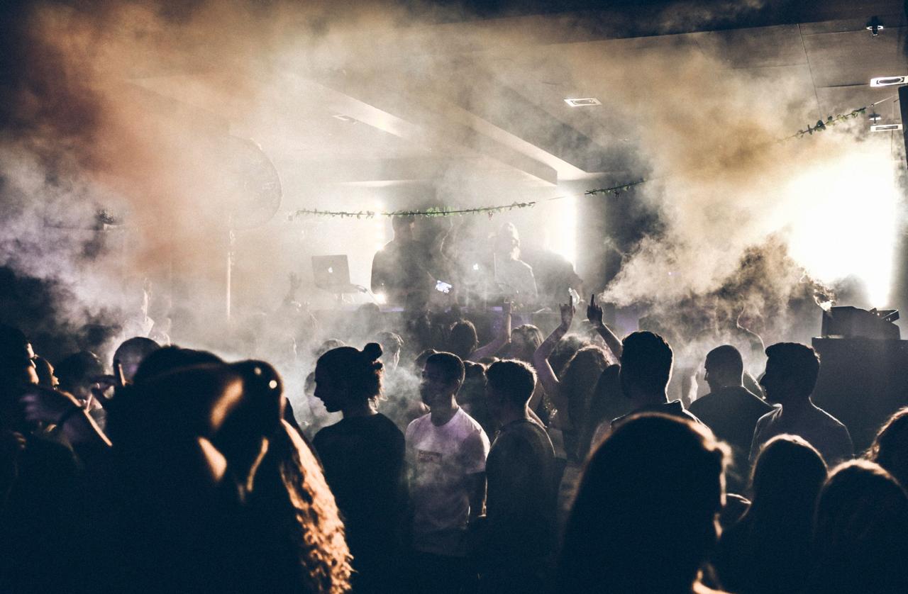 Nighttime beach club scene with DJ, dance floor, and ocean backdrop