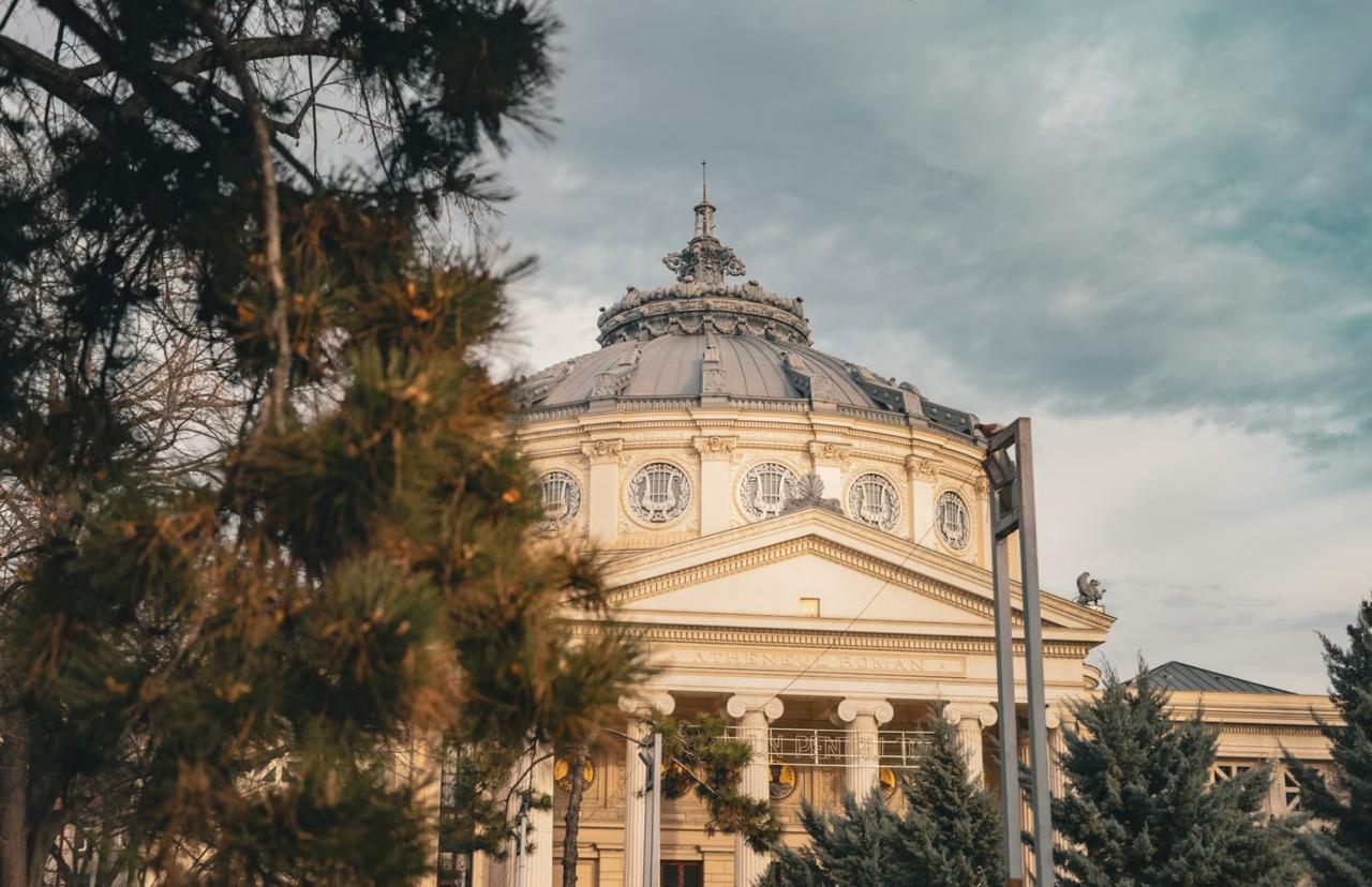 Domed concert hall of the Romanian Athenaeum with gilded balconies and a circular historical fresco