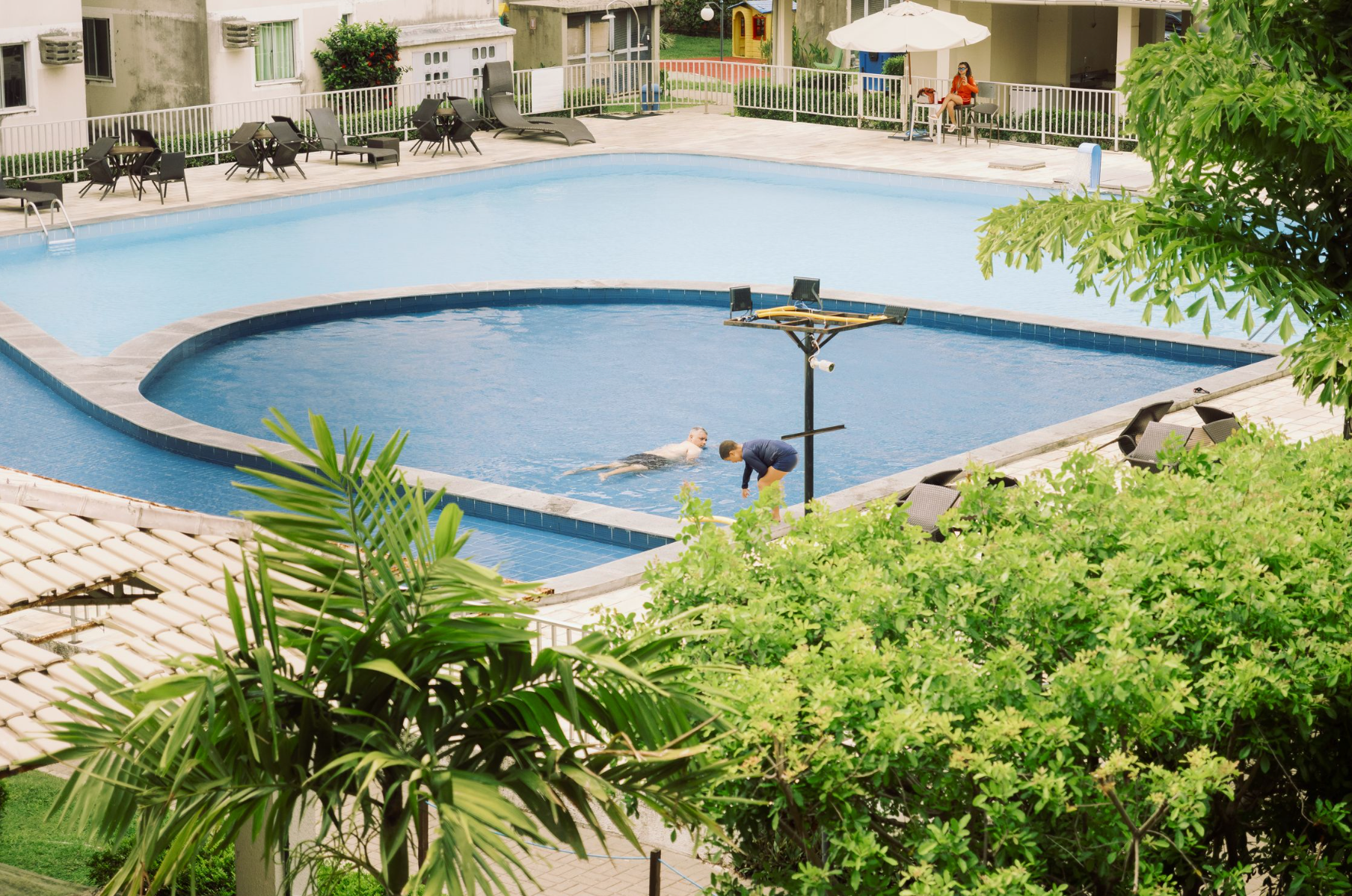 Swimmers relaxing in a steaming indoor thermal pool surrounded by palm trees at Therme București