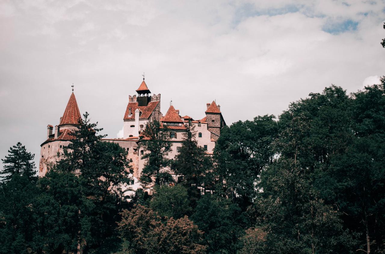 Bran Castle's whitewashed walls and red-tiled towers perched on a rocky hilltop in Transylvania
