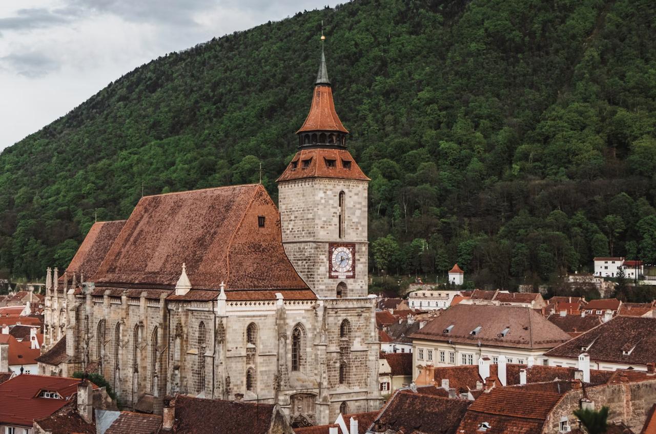 Pastel-colored baroque buildings around Council Square in Brașov with Tampa Mountain behind