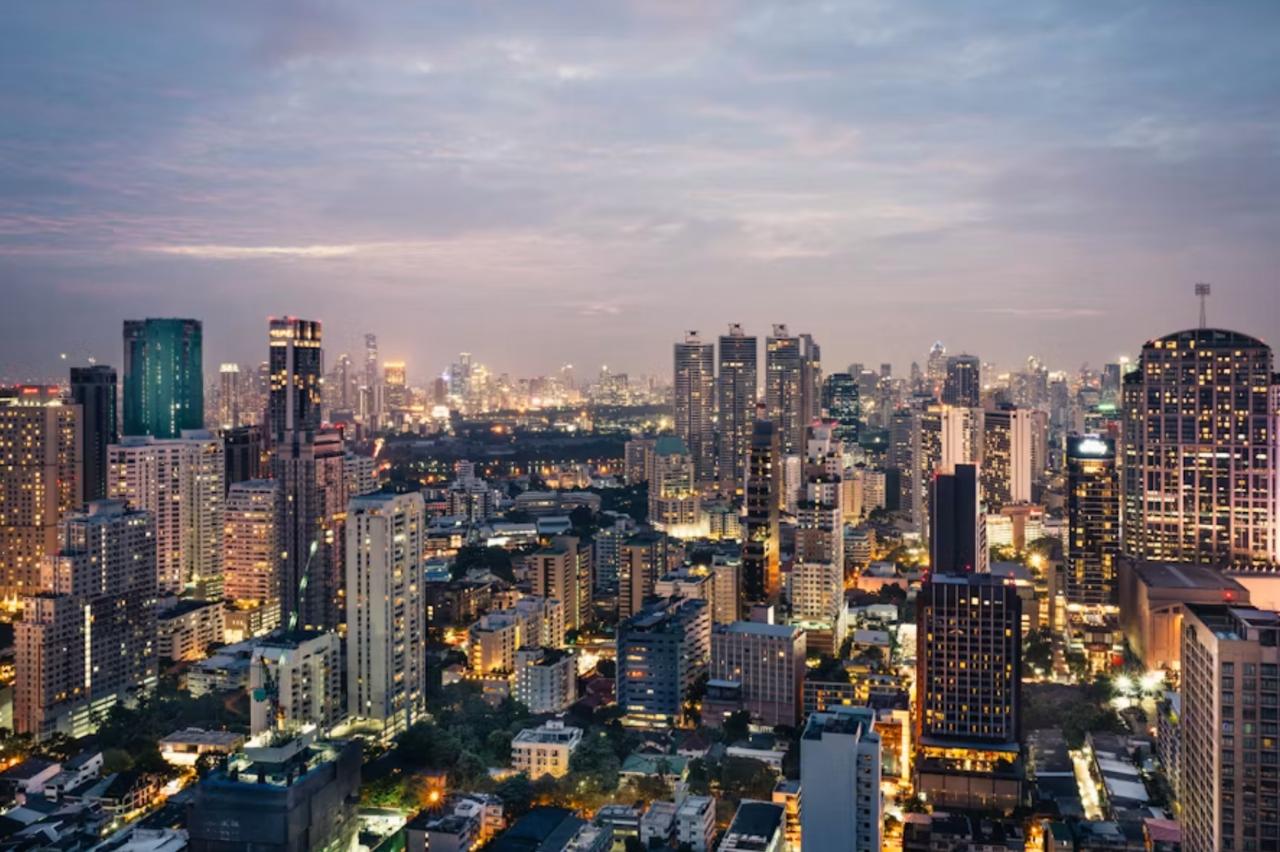 Bangkok skyline glowing beside the Chao Phraya River at sunset.