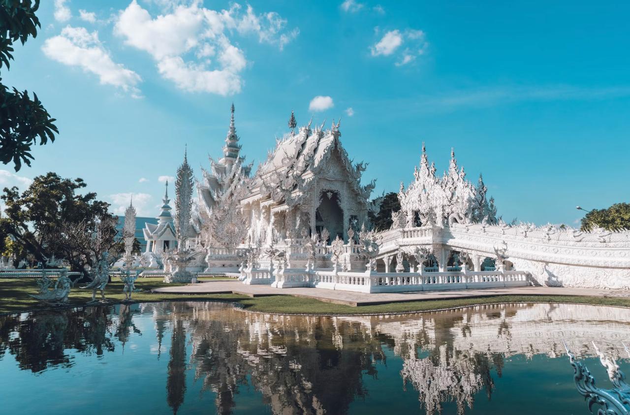 The White Temple reflecting beneath clear blue skies in Chiang Rai.