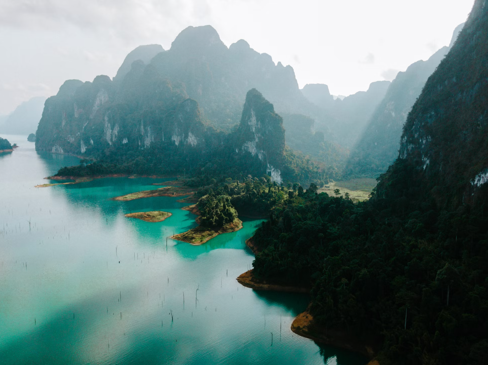 Emerald rainforest lake surrounded by towering limestone cliffs in Khao Sok.